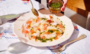 Préparation d'un carpaccio de bar frais avec pamplemousse, oignon rouge et une vinaigrette aux herbes.