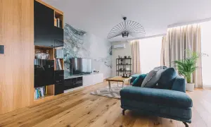Nowoczesny salon z sofą w odcieniach turkusu i szarości, gdzie dominują zimne kolory. Marmurowa ściana dodaje elegancji.