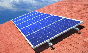 Paneles solares azules sobre un tejado rojo, capturando la energía del sol. ¿Quién inventó las placas solares?