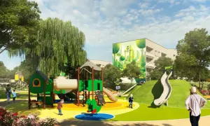 Kolorowy plac zabaw z zielonymi elementami, zjeżdżalniami i huśtawkami, na tle budynku z muralem.