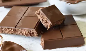 En fransk chokladtårta med krispigt fyllning, uppdelad i bitar. En sked med chokladkräm syns i förgrunden.