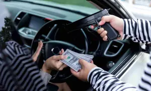 Un homme en pull rayé menace une personne en voiture avec un pistolet, exigeant de l'argent. Scène d'extorsion.