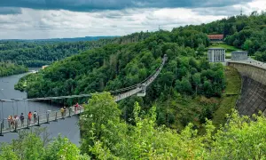 Hängebrücke über die Rappbodetalsperre, ein beliebtes Ausflugsziel im Harz. Menschen spazieren über die Brücke, umgeben von grünen Wäldern.