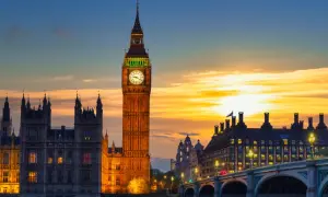 Wieża zegarowa Big Ben w Londynie o zachodzie słońca, z Parlamentem i mostem w tle.
