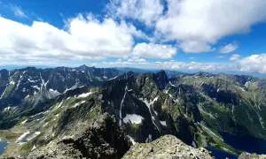 Widok na pasmo górskie Rysy, gdzie szlak wije się wśród skalistych zboczy i resztek śniegu.