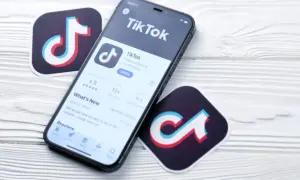 Telefon z aplikacją TikTok i logotypy platformy. Zastanawiasz się, ile zarabia się na tiktoku za 1000 wyświetleń?