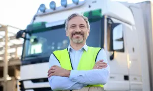 Un chauffeur souriant, en gilet fluo, prêt pour son passage aux mines poids lourds.