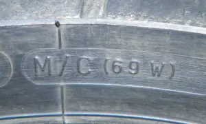 Napis "M/C (69 W)" wytłoczony na oponie motocyklowej.