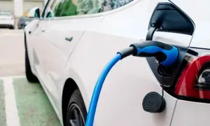 Sekrety doboru opon do aut elektrycznych: dlaczego zwykłe opony niszczą się szybciej? Biały samochód elektryczny podłączony do ładowania.