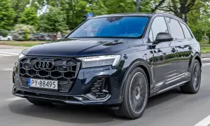 Ciemny Audi Q7 w ruchu ulicznym, z grillem i światłami LED. Sprawdź audi q7 cena i możliwości tego luksusowego SUV-a.