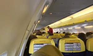 Wnętrze samolotu Ryanair, pasażerowie siedzą w rzędach. Na oparciach siedzeń widoczne są żółte tabliczki z instrukcjami bezpieczeństwa, co może uspokoić osoby zastanawiające się, czy Ryanair jest bezpieczny.