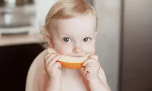 Ein süßes Baby genießt ein Stück Honigmelone.