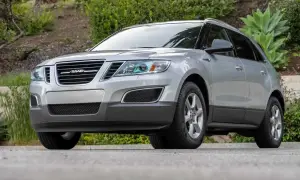 Silver Saab 9-4X SUV parkerad utomhus, med grönska i bakgrunden.