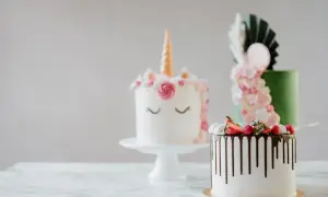 En förtrollande rosa tårta i enhörningsstil, bredvid en grön tårta med blommor och en vit tårta med chokladdryp och bär.