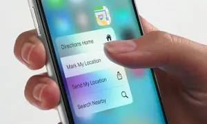 Dłoń naciska na ekran telefonu, aktywując menu z opcjami nawigacji. Funkcja 3D Touch pozwala na szybki dostęp do "Directions Home", "Mark My Location" i innych.