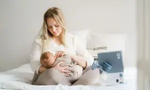 En mamma ammar sitt lilla barn. Bredvid dem står en bröstpump och dess förpackning.