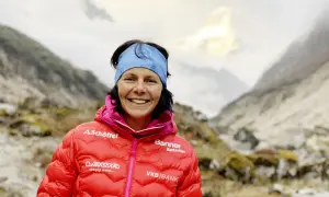 Kristin Harila, bereit für den K2, lächelt in die Kamera, umgeben von majestätischen Bergen.