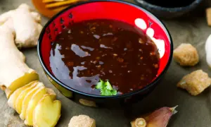 Sos teriyaki przepis: aromatyczny sos w miseczce, obok imbir, czosnek i cukier. Idealny do dań azjatyckich.