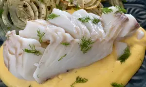 Saftigt vit fisk serveras med krämig sås och ugnsbakad fänkål, garnerad med dill.