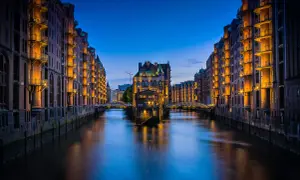 Nocny widok na Speicherstadt w Hamburgu, z kanałem i zabytkowymi budynkami magazynowymi oświetlonymi ciepłym światłem. To jedna z głównych hamburg atrakcje.
