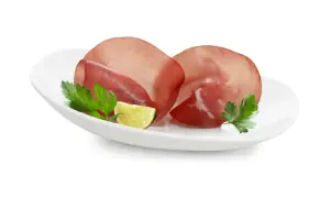 Fette di bresaola su piatto bianco con prezzemolo e lime. Ottima per un pasto leggero, scopri le calorie bresaola.