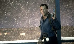 John McClane, med en gammal mobiltelefon i handen, står i snöstormen. Han är en del av rollistan i Die Hard 2.