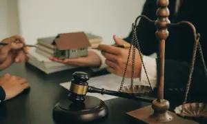 Sąd rozstrzyga sprawę o dziedziczenie ustawowe. Młotek sędziowski, waga sprawiedliwości i makieta domu symbolizują proces prawny.