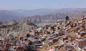 Färgglada hus klättrar uppför bergssluttningar i La Paz, bolivias huvudstad, med dramatiska berg i bakgrunden.