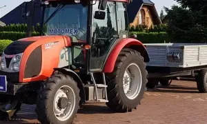 Czerwony Zetor z przyczepą, gotowy do pracy. Posiadanie prawa jazdy na traktor otwiera drogę do takich maszyn.
