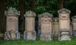 Nagrobki z inskrypcjami hebrajskimi, niektóre z widocznymi pęknięciami, sugerującymi wady materiałowe płyt granitowych.