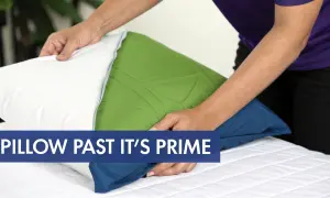 Hands adjust a pillow, hinting at how often should you change your pillows on your bed.