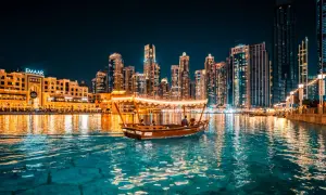En båt glider fram på vattnet i Dubai i december, med upplysta skyskrapor som bakgrund.