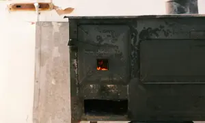 Stary piec na drewno z widocznym ogniem. Komin jest metalowy, ale jego jaka średnica komina do pieca na drewno nie jest widoczna.