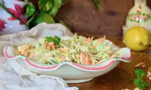 Deliciosa ensalada de col cremosa con zanahoria rallada, coronada con nueces y perejil. Perfecta para acompañar cualquier comida.