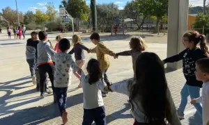Niños jugando en círculo, tomados de la mano, en una actividad de juegos de conocimiento del medio al aire libre.
