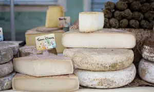 En härlig samling fransk ost, inklusive en "Tomme Chèvre", staplade på ett bord.