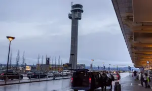 Wieża kontrolna na oslo lotnisko, deszczowa pogoda, ludzie z bagażami wsiadają do vana.