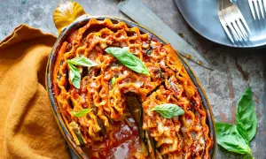 Lasagne aubergine gratinée, garnie de basilic frais, dans un plat ovale. Un délice italien réconfortant.
