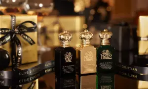 Trzy butelki najdroższych perfum Clive Christian w złotych opakowaniach, ozdobione czarną wstążką z logo marki.