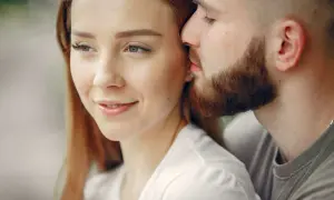 Un uomo sussurra dolcemente all'orecchio di una donna, un gesto che rivela cosa fa innamorare un uomo: la tenerezza e l'intimità.