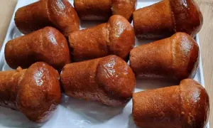 Un vassoio bianco pieno di deliziosi babà dorati, inzuppati in uno sciroppo lucido.