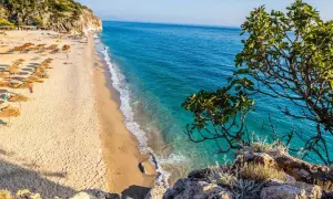 Piękna plaża w Albanii z turkusową wodą i rzędami parasoli. Ceny wakacji w Albanii są przystępne, a widoki zachwycające.