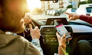 Kierowca i pasażerka sprawdzają nawigację w telefonie, ustalając trasę i czas podróży.