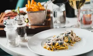 En tallrik med typisk italiensk mat: pasta med kyckling och parmesan, serverad med pommes frites och vin.