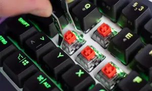 Nahaufnahme von Tastatur-Switches mit roten Kappen, die Unterschiede zeigen. Grüne Beleuchtung schimmert durch.