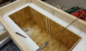 Wooden frame with OSB interior, insulated with white foam. A pencil and ruler are visible.