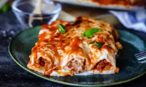 Herzhafte cannelloni mit hackfleisch, überbacken mit geschmolzenem Käse und Tomatensauce, garniert mit frischem Basilikum.