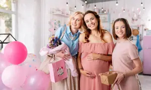 Trzy uśmiechnięte kobiety świętują baby shower po polsku. W tle balony i prezenty.