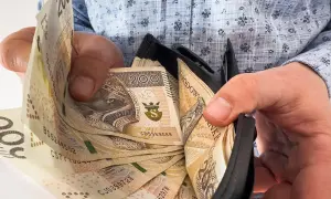 Ręce trzymają portfel z banknotami 200 zł. Ile trzeba przepracować, by tyle zarobić?