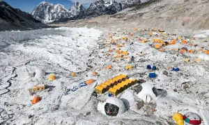Zahlreiche bunte Zelte auf schneebedecktem Geröllfeld am Fuße des Mount Everest. Ein Basislager, das die Herausforderungen des Gipfels widerspiegelt.